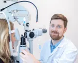 Okulista przeprowadza test na nadwzroczność u pacjentki, badając jej wzrok za pomocą specjalistycznego sprzętu.