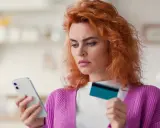 Zastanawia się, co to jest dip, przeglądając ofertę w telefonie z kartą w dłoni.