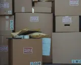 Stos kartonów, w tym oznaczone jako "FRAGILE", gotowych do wysyłki. Czy do reklamacji potrzebny jest karton? Zazwyczaj tak, aby zabezpieczyć towar.