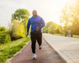 Glücklicher Mann beim Laufen im Park. Sein Training laufen im Sonnenschein macht ihn fit und gesund.