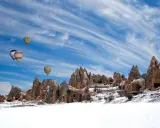 Balony unoszą się nad ośnieżonymi formacjami skalnymi w Kapadocji. Czy w Turcji pada śnieg? Tak, zimą krajobraz potrafi być bajkowy.