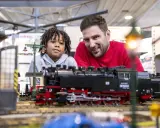 Vater und Sohn bestaunen detailreiche Modelleisenbahnen auf der Modellbaumesse Dortmund.