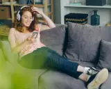 Dziewczyna z rudymi włosami słucha muzyki Indili, przeglądając telefon na kanapie. Jej uśmiech sugeruje, że to jej ulubiona love story.