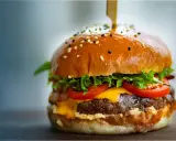 Un délicieux burger, avec sa brioche dorée, sa viande juteuse, son fromage fondant, sa laitue croquante et ses tomates fraîches. On se demande d'où vient le burger, ce classique indémodable.