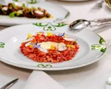 Delicioso tartar de atún fresco, adornado con láminas de trufa negra, flores comestibles y un toque de amarillo vibrante.