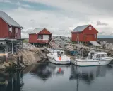 Norwegia: praca w norwegii dla par z zakwaterowaniem. Czerwone domki rybackie i łodzie przy skalistym brzegu.