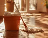 Seau orange avec serpillère et serviette, prêt pour le nettoyage de terre cuite avec bicarbonate de soude.