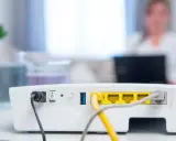 Router vom Strom trennen wie lange? Das Bild zeigt die Rückseite eines weißen Routers mit Netzteilanschluss, Schalter und LAN-Ports.
