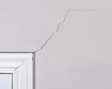 Pęknięcia na suficie akryl, widoczne nad białym gzymsem, tworzą nieregularny wzór.