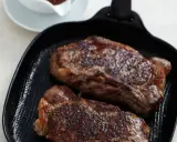 Zwei saftige Rumpsteaks braten in einer Grillpfanne, perfekt gewürzt und bereit zum Genuss.
