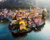 Färgstark by vid en sjö i norra Italien, med hus i gult, rosa och orange som klättrar uppför en sluttning.