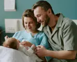 Szczęśliwi rodzice z noworodkiem w szpitalu. Dowiadują się o świadczenia po urodzeniu dziecka.
