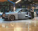 Elegancki szary Rolls-Royce Phantom z otwartymi drzwiami, obok którego stoi kobieta. Poznaj jego wyjątkową rolls royce phantom cena.