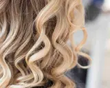 Piękne, falowane włosy z subtelnym balejażem blond, dodającym im blasku i głębi.