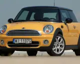 Żółty Mini Cooper, jedna z nowszych generacji, z czarnym dachem i felgami.