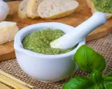 Frisches Basilikum-Pesto im Mörser, bereit zum Genießen. Dazu Brot, Parmesan und Pasta – so einfach ist basilikum pesto selber machen.