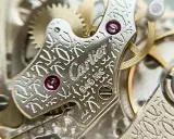 Dettaglio del movimento di un orologio Cartier, con incisioni guilloché e rubini. La joux perret, un capolavoro di precisione.