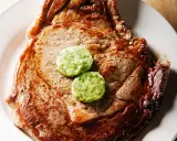 Un savoureux steak de bœuf, parfaitement grillé, est garni de deux rondelles de beurre maître d'hôtel, prêt à fondre.
