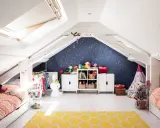Kreative kinderzimmer dachboden ideen: zwei Betten, Spielzeug, Kleiderständer und ein Sternenhimmel an der Wand schaffen eine gemütliche Atmosphäre.