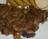 Pyszna kaszanka z patelni, duszona z cebulką, podana z ogórkiem kiszonym i kromką chleba.