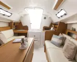 L'intérieur d'un voilier moderne, avec des banquettes en cuir, une table en bois et des hublots. Le premier 25 interieur est lumineux et spacieux.