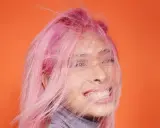 Frauenkopf mit pinken Haaren, die im Wind wehen. Ein Antistatik-Spray für Haare hätte hier Wunder gewirkt.
