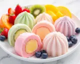 Assortiment coloré de mochis glacés aux fruits, parfaits pour une recette mochi glacé facile et gourmande. Fraises, kiwis, mangues et myrtilles accompagnent ces délices.