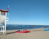 Torre di salvataggio e barchini sulla spiaggia di Rimini, pronti per nuove storie di mare.