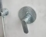 Mitigeur thermostatique de douche entartré, prêt à démonter sans vis. Le levier est en position basse.