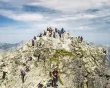 Rysy jak się przygotować: tłum turystów na szczycie, skaliste zbocza, widok na Tatry. Warto zabrać wodę i mapę.
