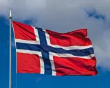 Norweska flaga powiewa na wietrze. W tle błękitne niebo z chmurami. Takie są prace, gdy jest piękna pogoda.