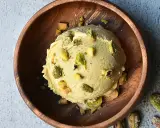 Cremoso helado de pistacho con trozos de pistacho en un cuenco de madera.