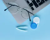 Okulary, pojemnik na soczewki i pęseta leżą obok laptopa. Czy można nosić soczewki i okulary jednocześnie?