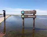 Witaj w polskim parku narodowym Ujście Warty! Droga zalana wodą, a obok tablica powitalna.