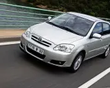 Srebrna Toyota Corolla 2004 na moście, z widokiem na wodę i las.