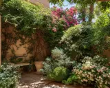 Un patio soleado con exuberantes plantas trepadoras que no ensucian, cubriendo muros y creando un oasis verde con flores rosas y blancas.