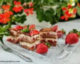 Pyszne tiramisu truskawkowe z warstwami biszkoptu, kremu i świeżych truskawek, posypane kakao i udekorowane owocami.