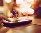 Palec dotyka ekranu telefonu, a nad nim pojawiają się dymki czatu. Dowiedz się, jak odzyskać wiadomości z kosza w telefonie.