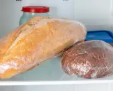 Deux pains emballés dans du film plastique, un pain blanc et un pain brun, sont rangés dans le frigo.