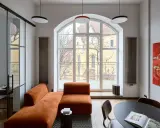 Nowoczesny salon z pomarańczową kanapą, czarnym stolikiem i obrazem. Jakie dodatki podkreślają styl?