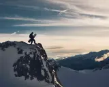Sylwester w Alpach: snowboardzista na szczycie góry, gotowy na zjazd. W tle majestatyczne, ośnieżone szczyty i dramatyczne chmury.