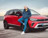 Joven apoyada en un Opel Crossland X rojo. Evita problemas con la correa de distribución de tu Opel Crossland X con un mantenimiento adecuado.
