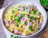 Fusilli-Nudeln mit Erbsen und Schinken in einer cremigen schinken sahne sauce, bestreut mit schwarzem Pfeffer.