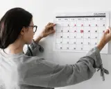Mujer revisa calendario, marcando días. No me baja la regla y no estoy embarazada, preocupación en su rostro.