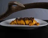 Un piatto di pasta fresca con ragù di cinghiale, un'autentica esperienza di mangiare toscano, con un palco di cervo sullo sfondo.
