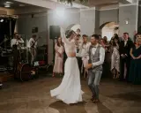 Para młoda tańczy na parkiecie podczas wesela w remizie. W tle zespół gra muzykę, a goście obserwują.