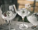 Drei Gläser mit Gin Tonic Water, gefrorene Eisbälle mit Kräutern und Beeren.