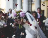 Płatki róż i ryżu sypią się na parę młodą. Słychać radosne okrzyki gości, a ksiądz na ślubie błogosławi nowożeńców.