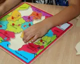Dziecko układa puzzle z mapą Polski, ucząc się regionów. To świetne gry dydaktyczne w przedszkolu.