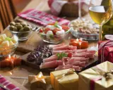 Eleganckie menu na sylwestra w domu: wędliny, sery, oliwki, pomidorki z mozzarellą, orzechy, wino i prezenty.